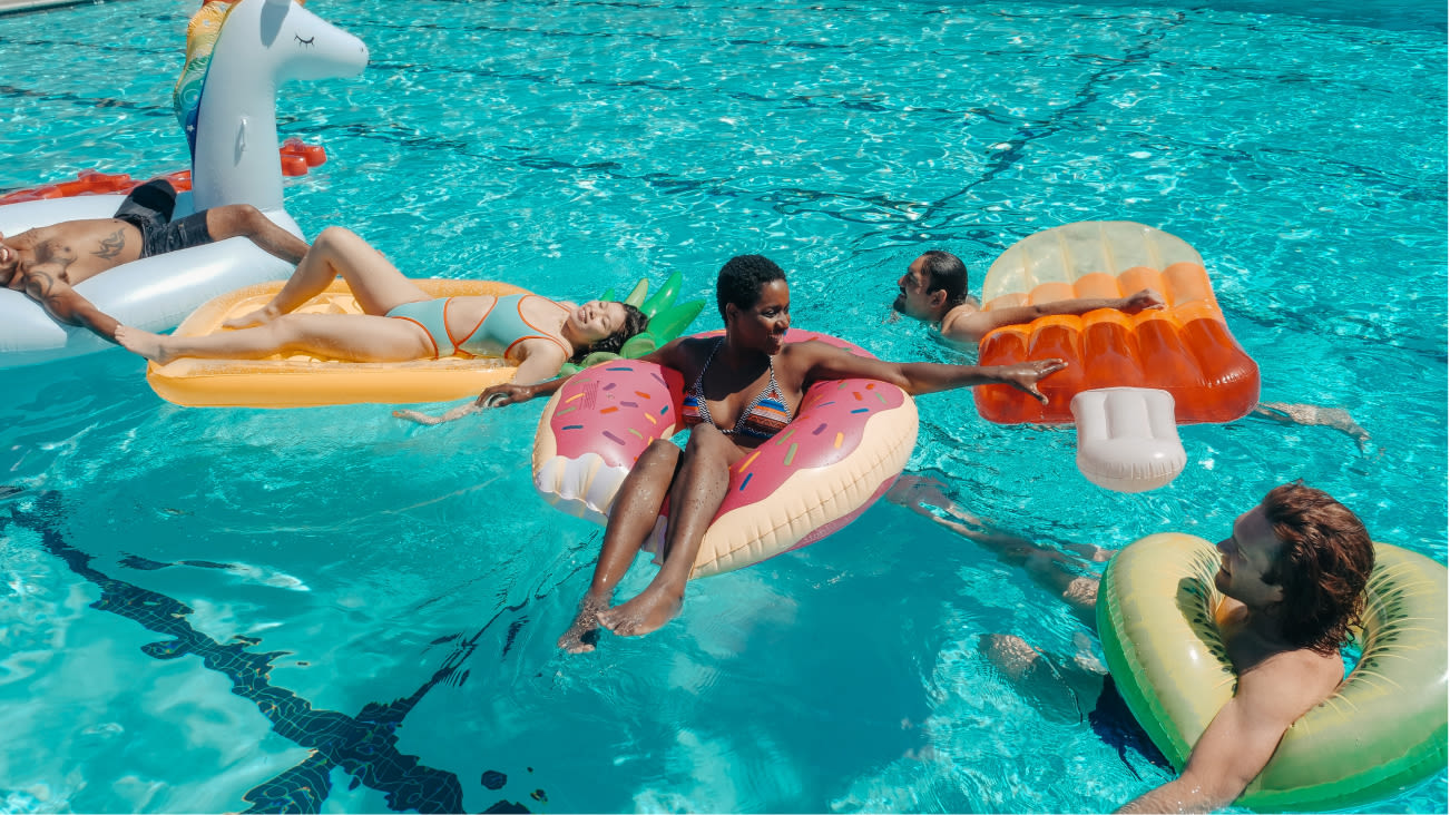 People cooling off in the pool with floaties.