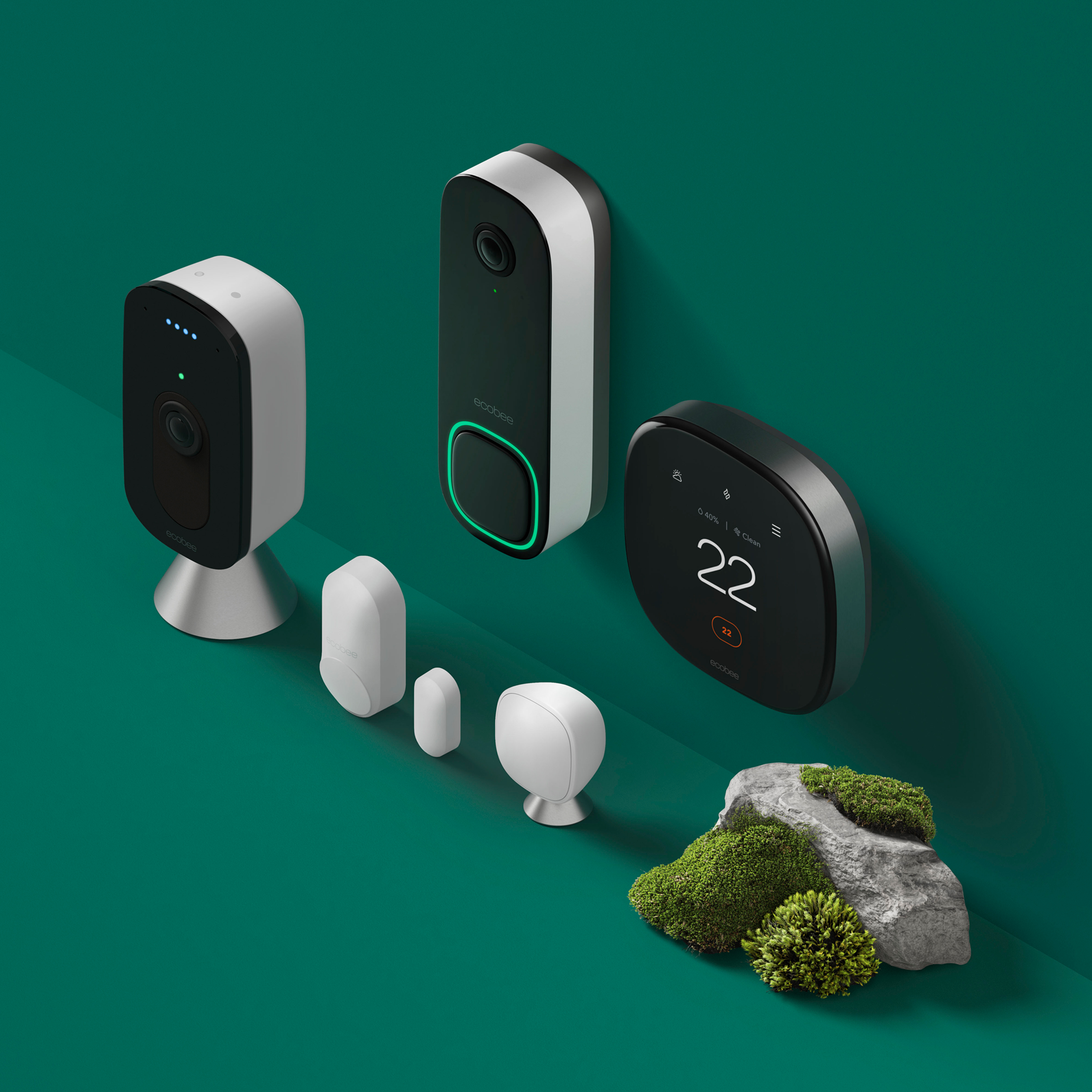 ecobee thermostat, Smart Doorbell Camera, SmartCamera with voice control and sensors sitting on a green background near a grassy rock.