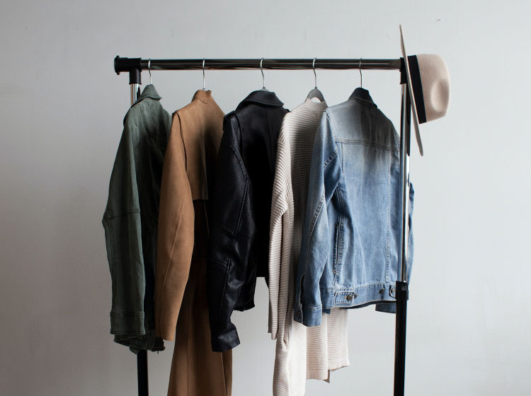 A clothing rail with five jackets and a hat.