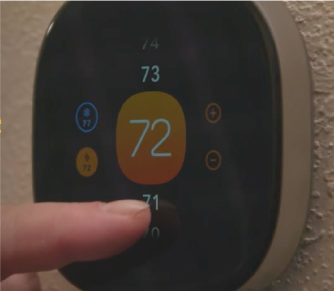 A finger presses the touch screen of an ecobee thermostat