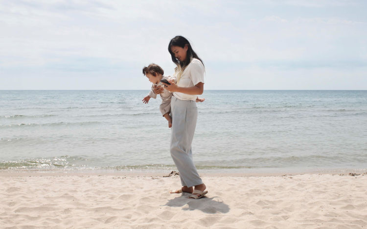 Woman and baby on beach.