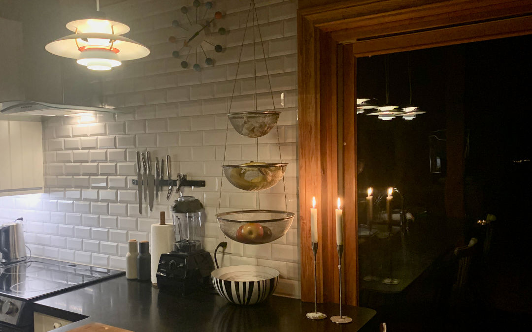 The warm light emitted from this pendant kitchen light and the candle coupled with the natural wood window frame add to the hygge in this modern kitchen.