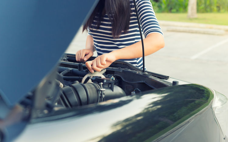 A woman checks her car's oil.
