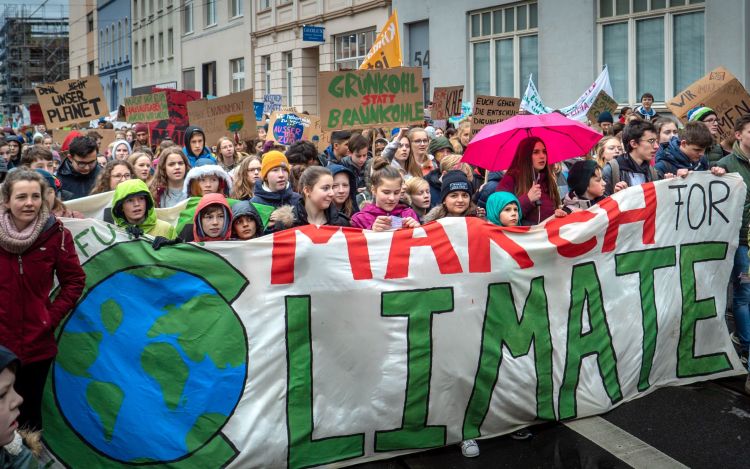 Thousands of young people participate in a 'March for Climate,' holding up banners and signs with messages about environmental action.