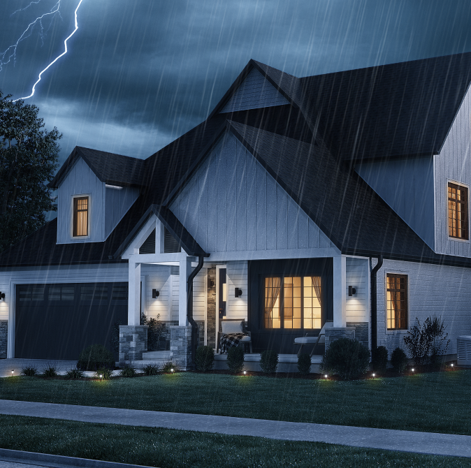 exterior of a house at night with lights on inside - lightning and rain are outside