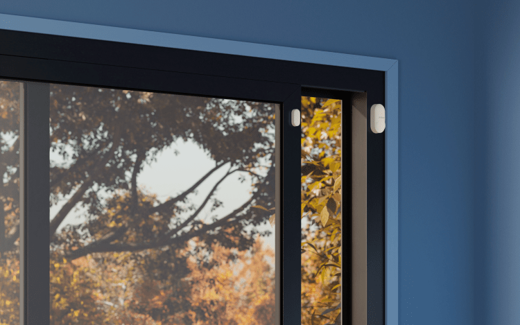 SmartSensor for doors and windows against window and blue wall.