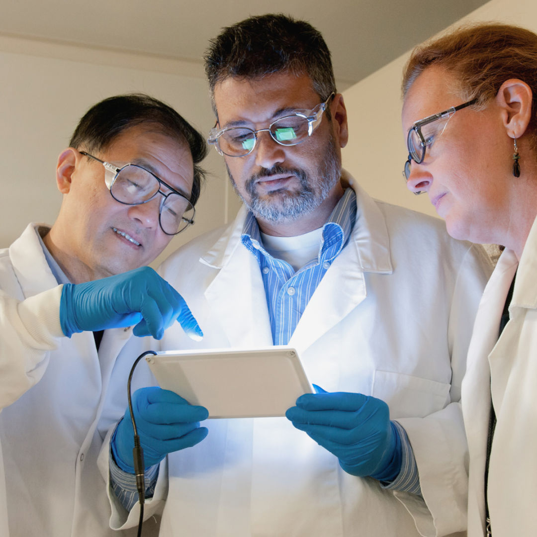 3 scientists look at the screen of a tablet