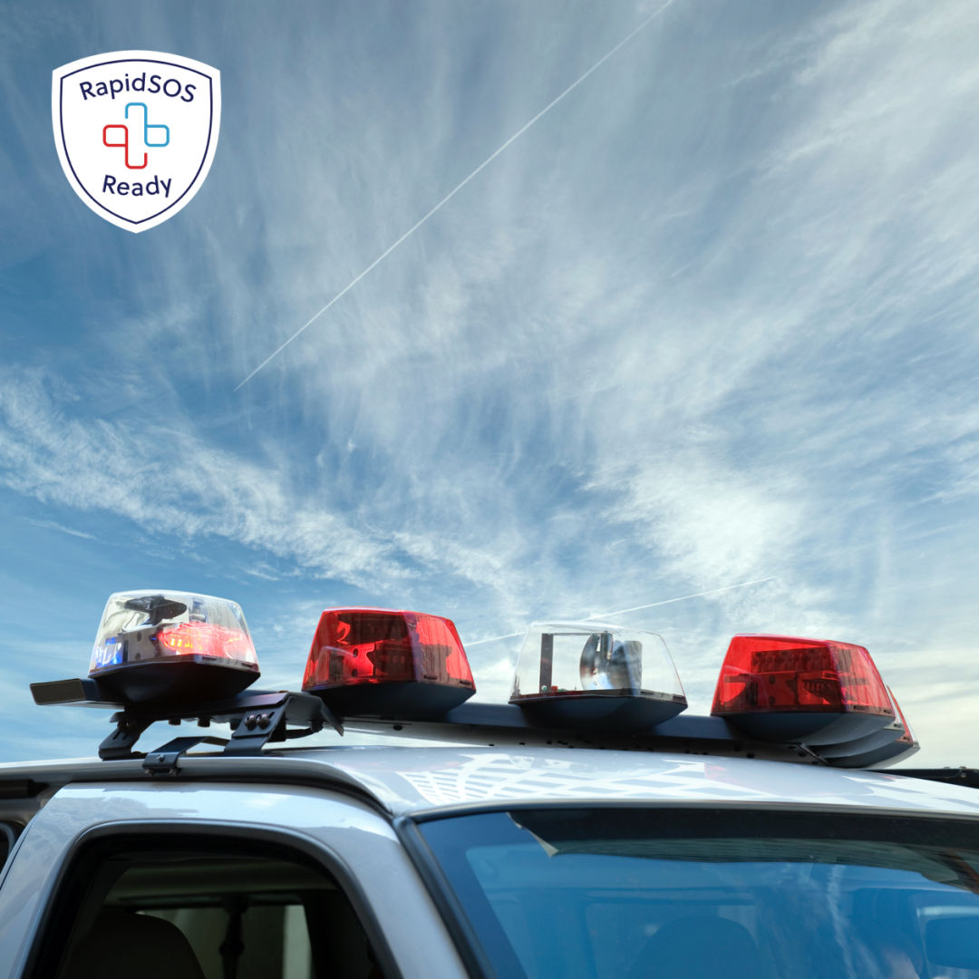 Lights on top of an emergency response vehicle against a blue sky. The RapidSOS Ready badge is in the corner.