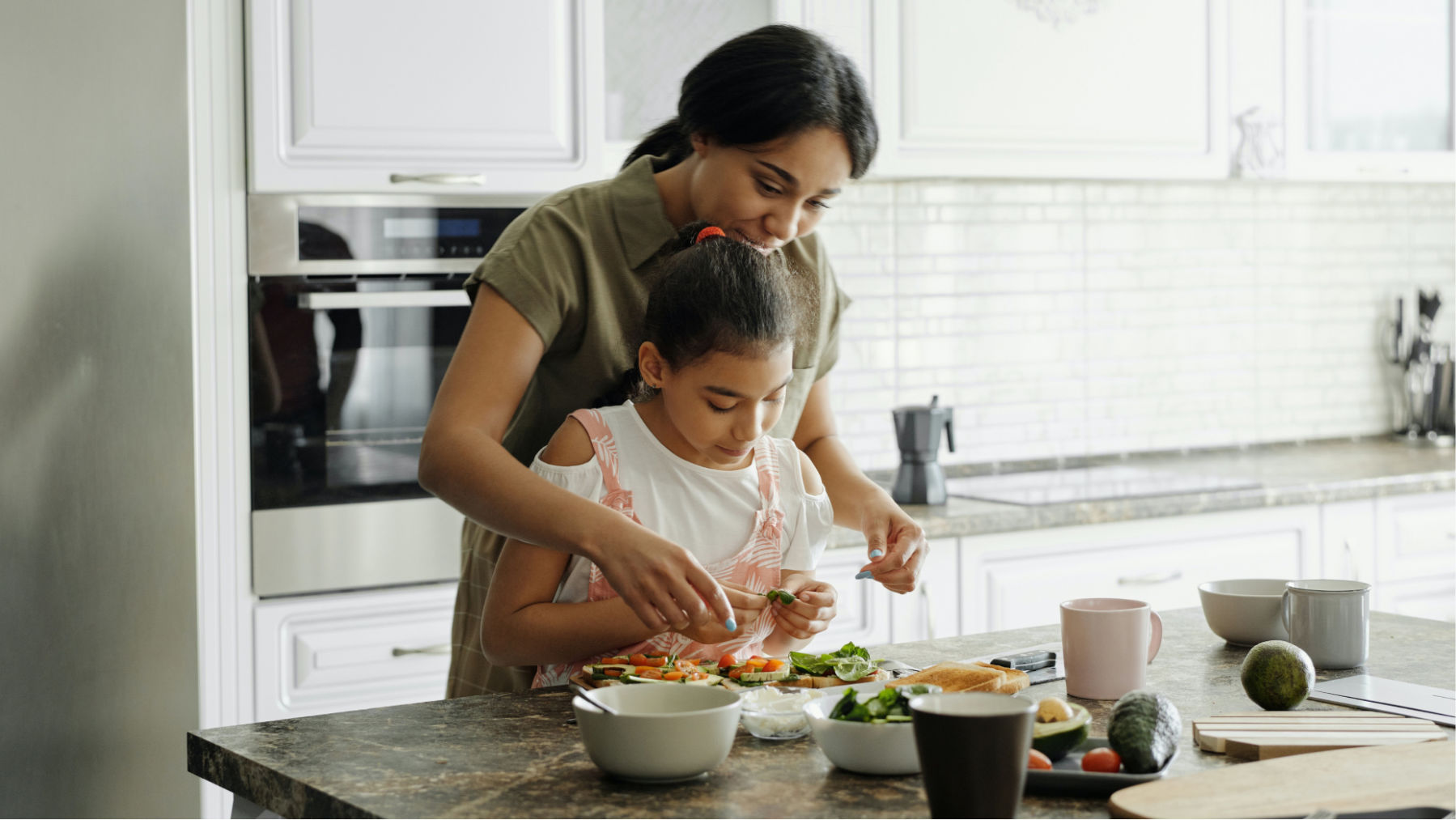 Mom and daughter in kitchen making sandwiches.