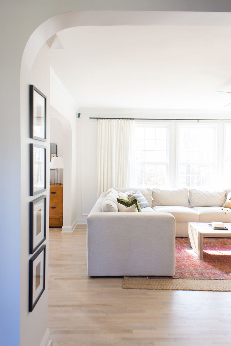 A bright living room with an ecobee SmartCamera on a shelf in an upper corner of the room.