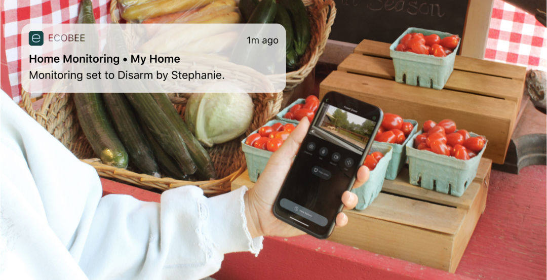 A hand holds a smartphone, while a notification from the ecobee app appears on screen.