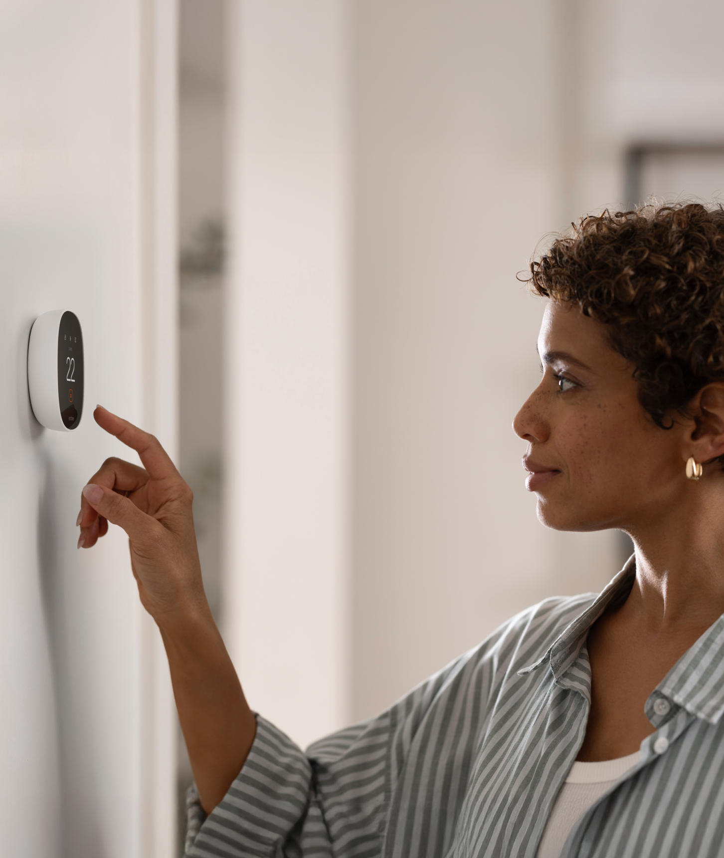 a person adjusts their smart thermostat essential