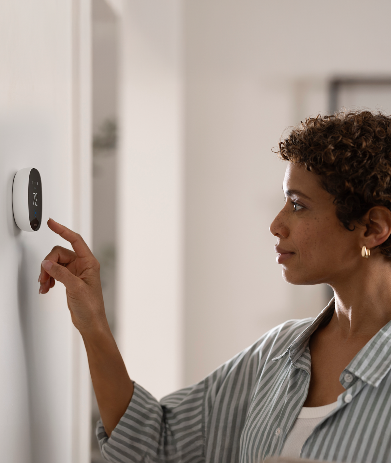 a person adjusts their smart thermostat essential