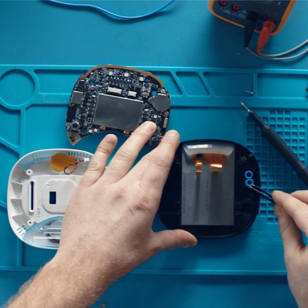 A pair of hands take apart an ecobee thermostat