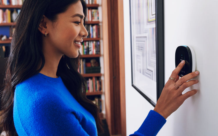 Lady in blue shirt sets the temperature on her ecobee thermostat.