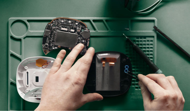 A pair of hands working on the inside of an ecobee thermostat.