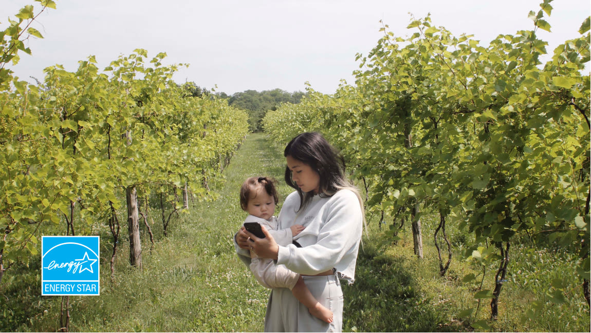Mom and daughter in a vineyard checking smartphone.