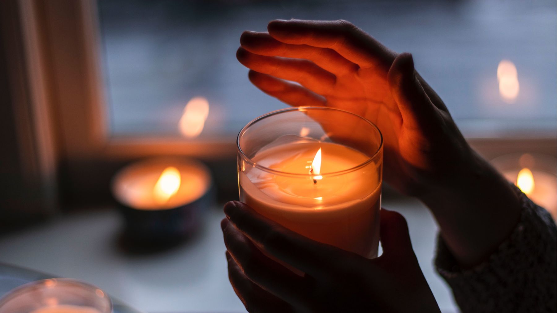 Person holding candle and covering flame.