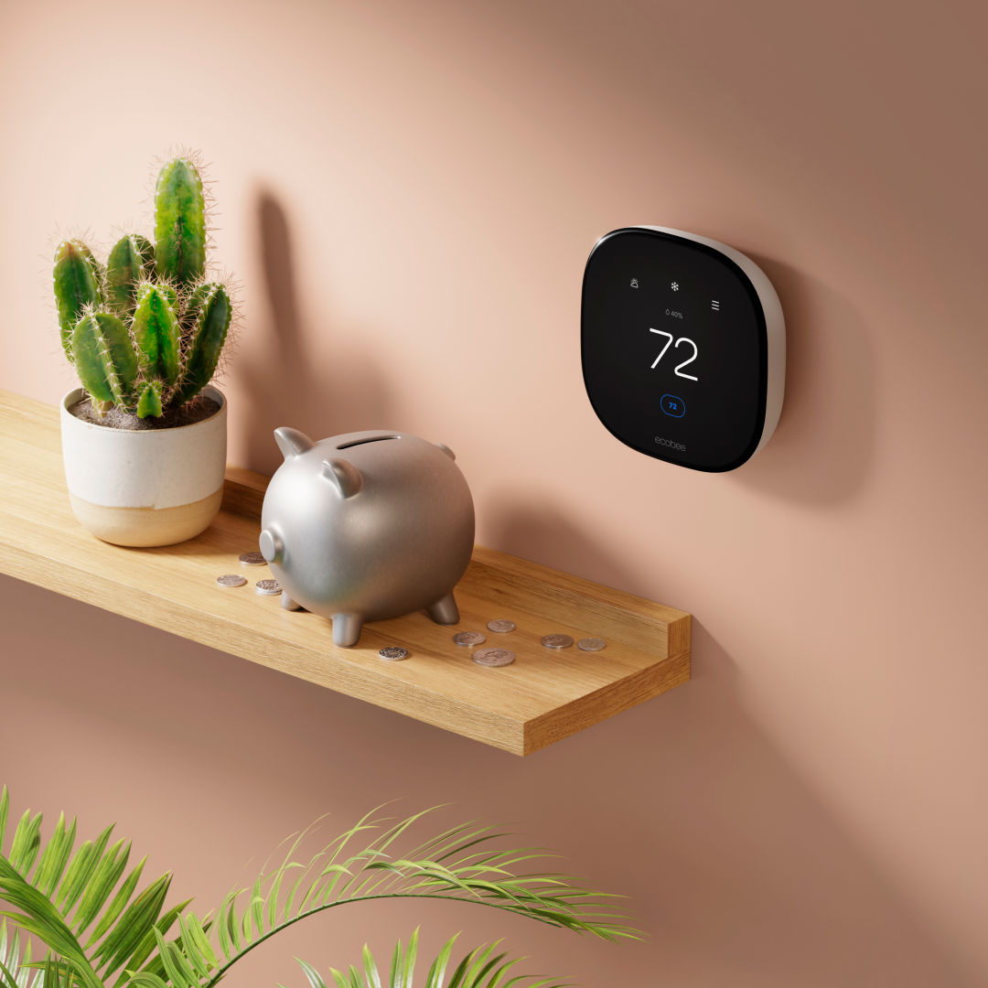 ecobee smart thermostat enhanced on a wall next to a shelf with a piggy bank with coins around it. 