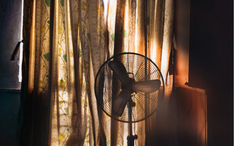 Image of a fan running in a home and curtains closed to block sunlight