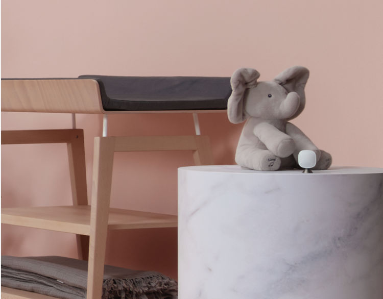 A stuffed elephant toy sits next to a changing table in a baby's room.