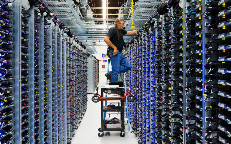 Google technician on ladder with (with scooter in tow) tending to server farm. 