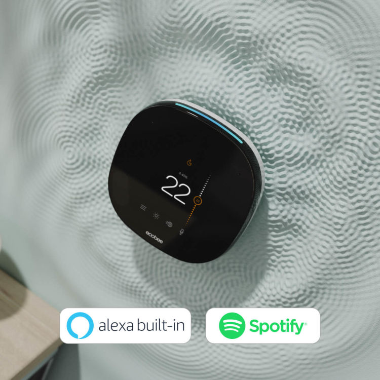 Smart thermostat on wall with alexa built-in logo and spotify logo hovering below.