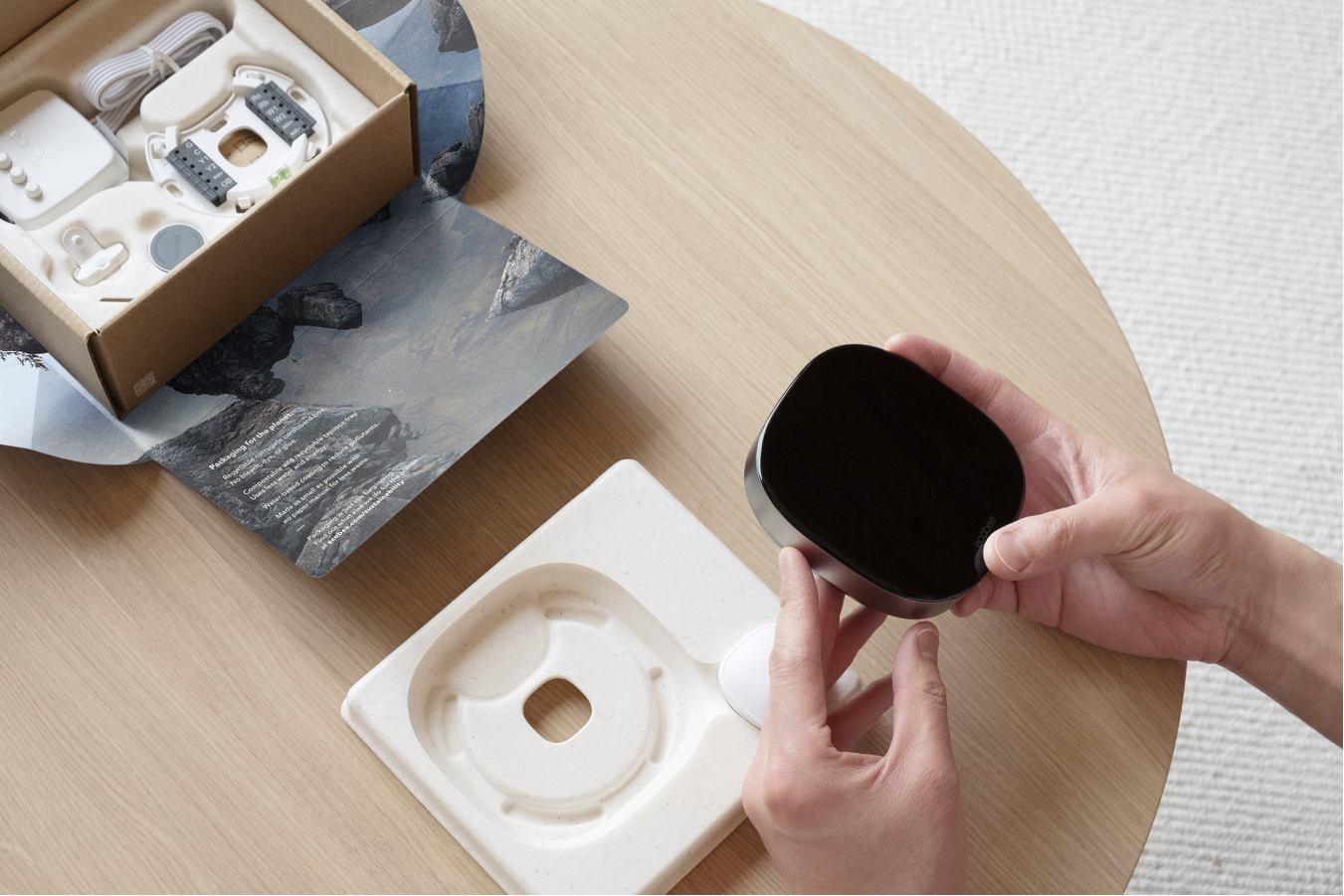 A pair of hands removes the ecobee Smart Thermostat Premium from the tapioca tray.