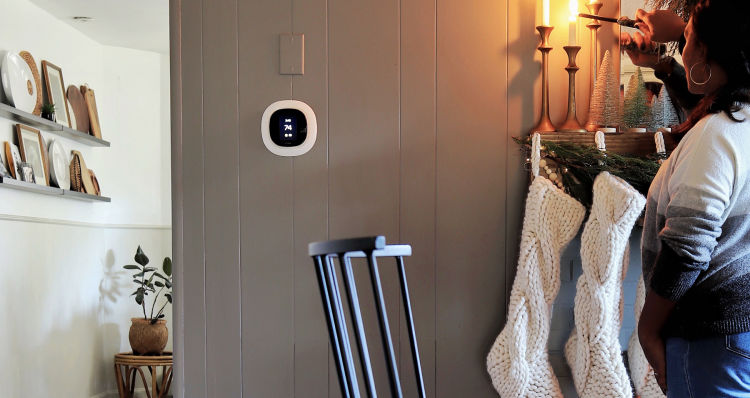 ecobee SmartThermostat with voice control display on the wall with woman lighting a candle above stockings.