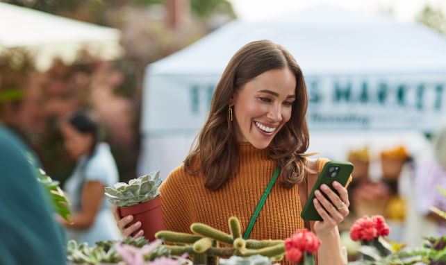 A woman shops while smiling at her phone