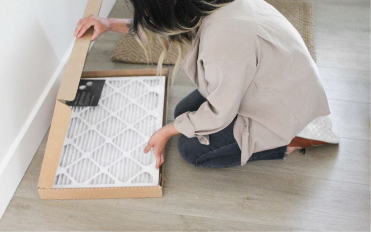 Woman bending down to open box of ecobee air filters.