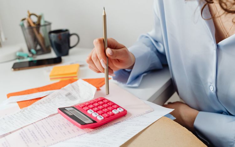 Woman with calculator and bills on her desk.