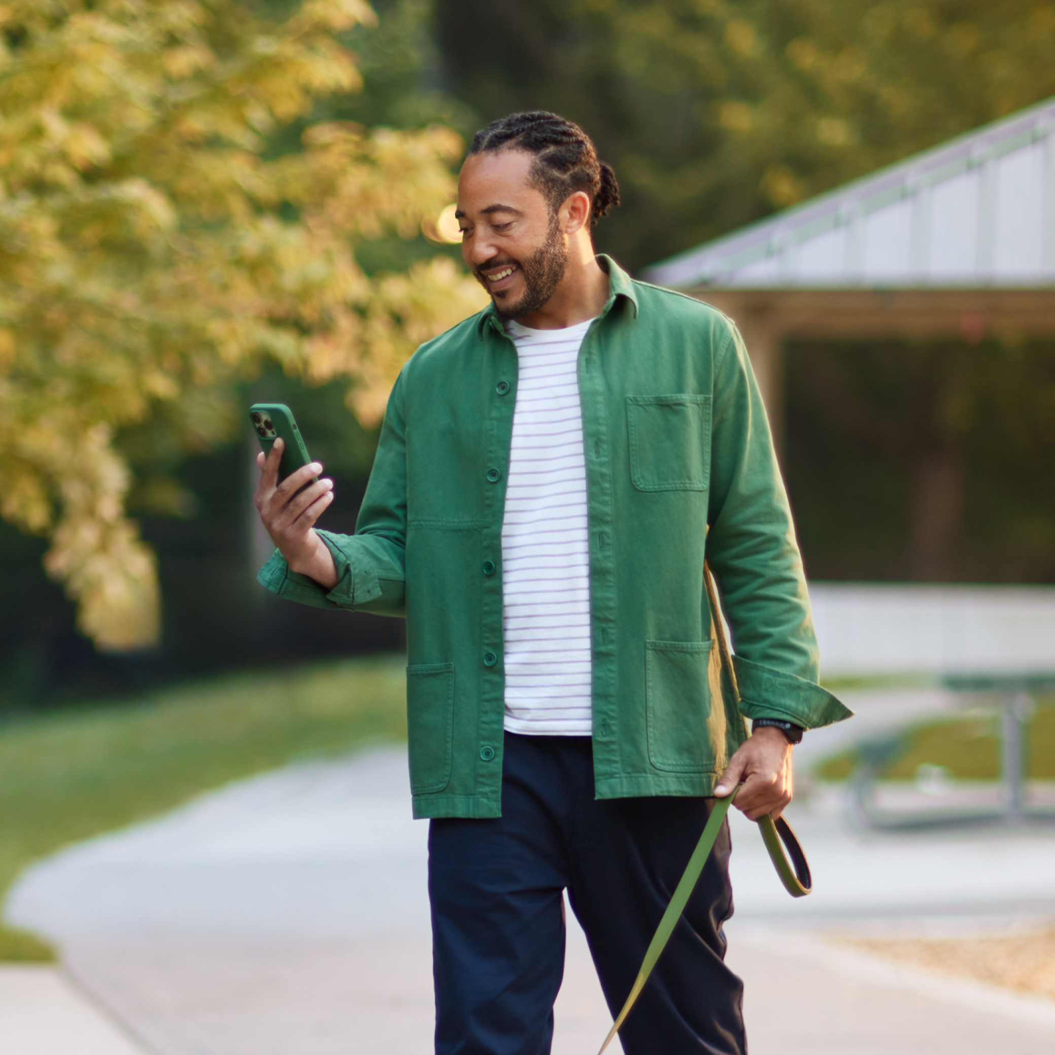 a man walking a dog holds his phone and smiles at it
