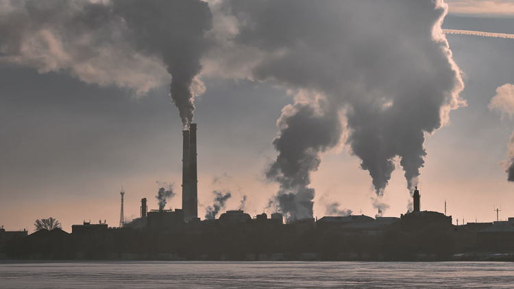 A landscape image of factory smokestacks billowing pollution.