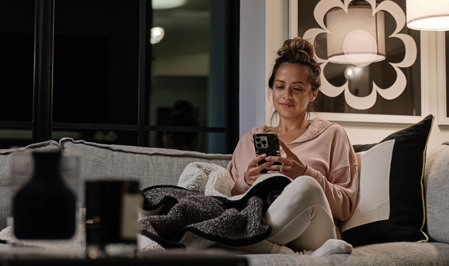 woman sitting on her couch looking at her phone