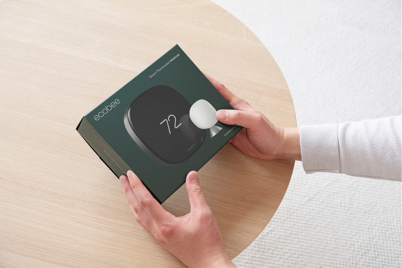 A pair of hands holds the box for an ecobee Smart Thermostat Premium