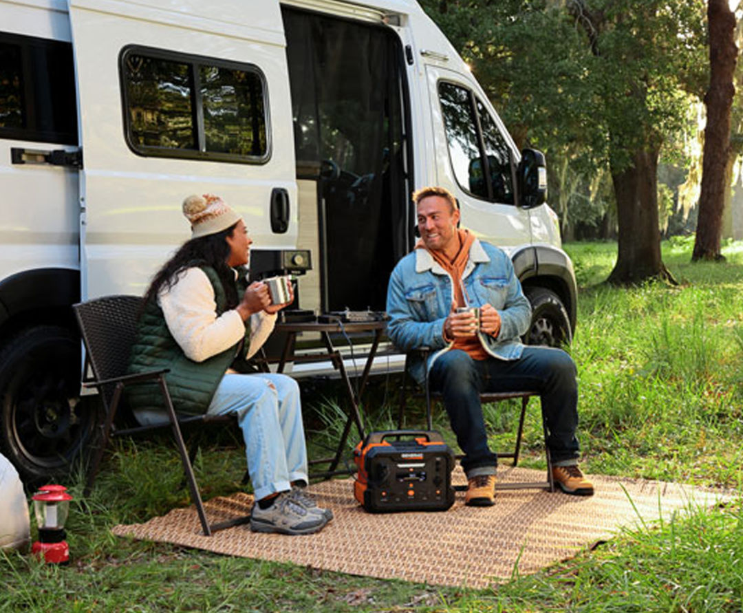 2 people sit outside a camper van with the Generac GB1000 Portable Power Station