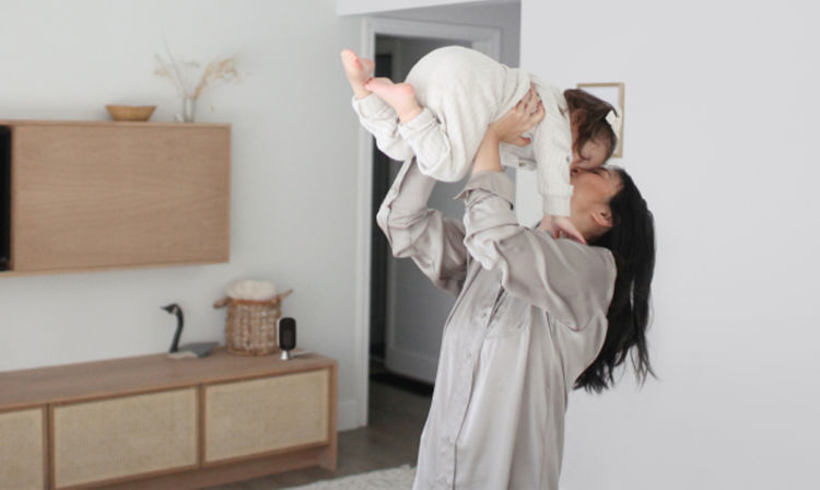 A woman plays with a baby; the ecobee Smart Camera is on a shelf in the background.