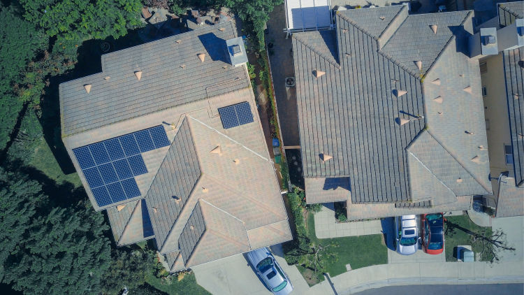 An aerial view of a house with solar panels installed on the roof