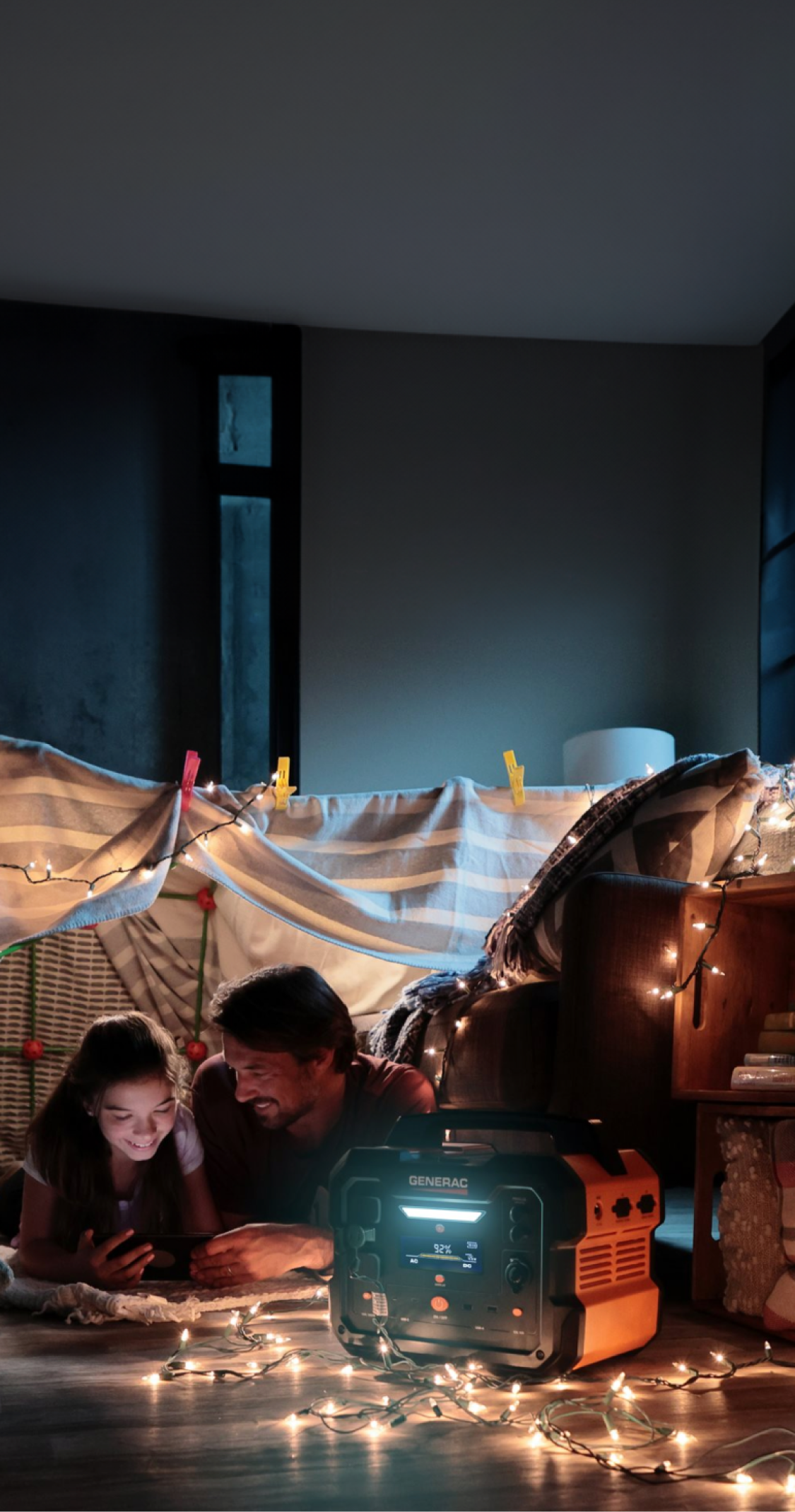 two people in a blanket fort with the Generac GB1000 providing power to string lights.