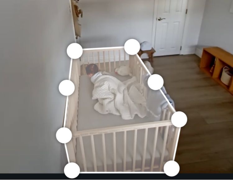 A baby sleeping in a crib with white dots superimposed over the edges of the crib.