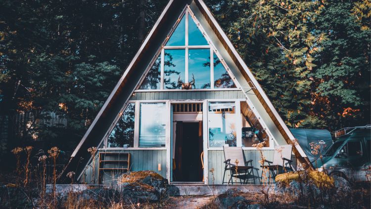 Image of a triangular tiny home surrounded by a forest