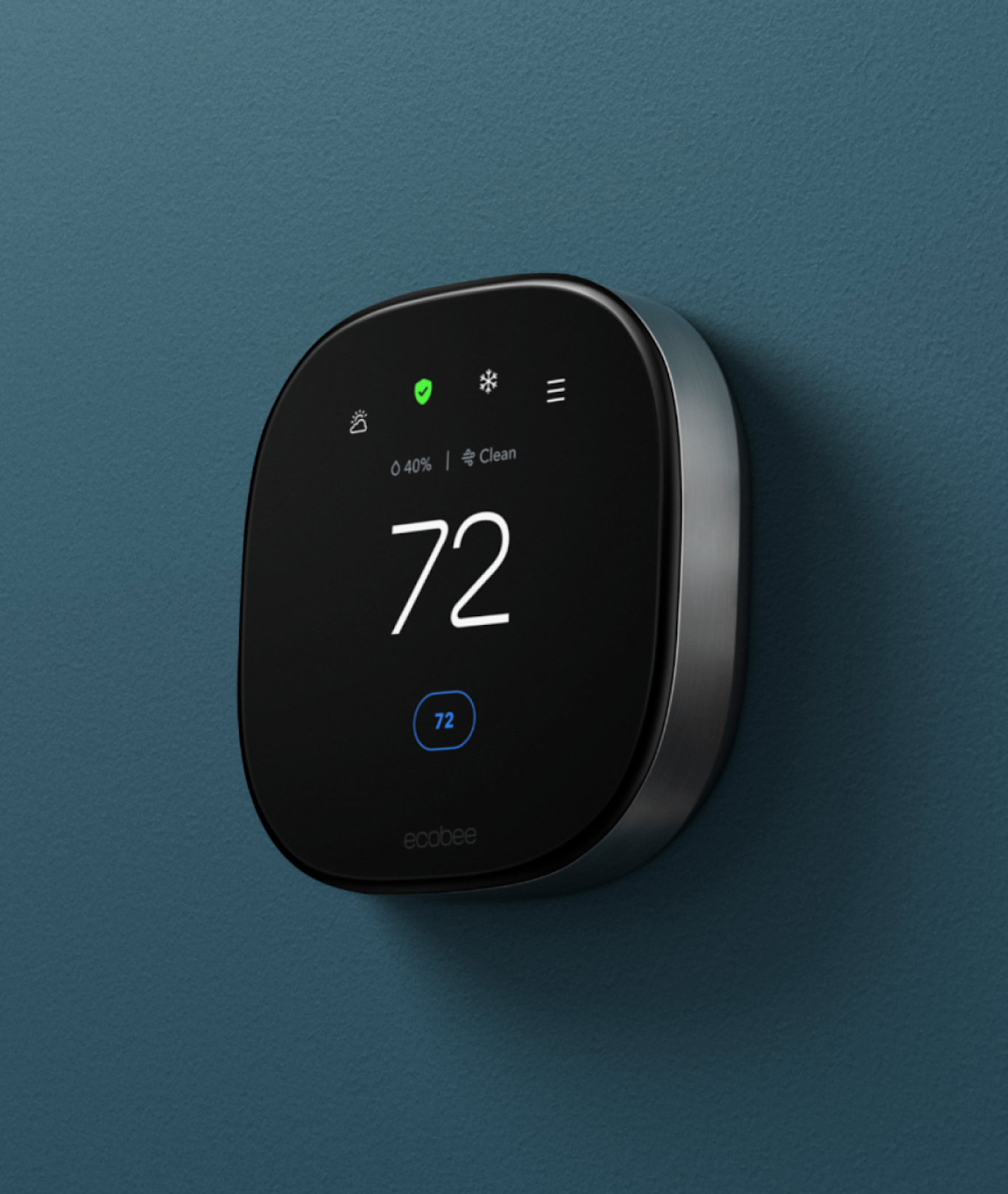 A smart thermostat is pictured mounted on a dark teal wall