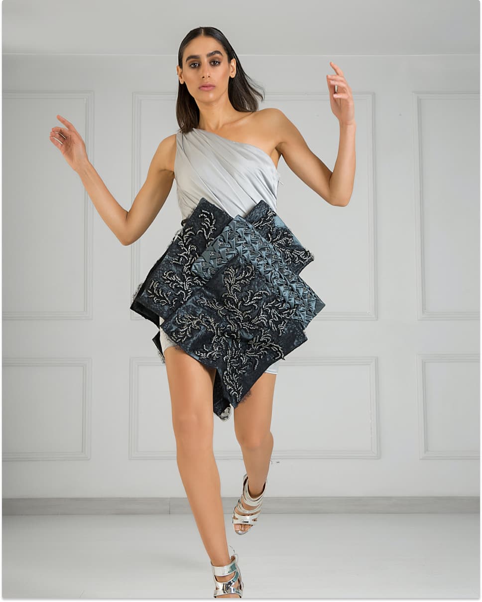 A person wearing a grey dress with some square designs