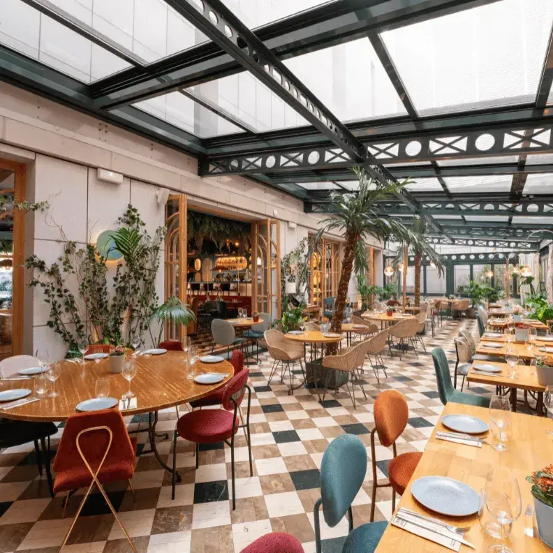 Un luminoso jardín interior con techos acristalados y vegetación exótica, Botania ofrece una experiencia culinaria rodeada de estilo y naturaleza.