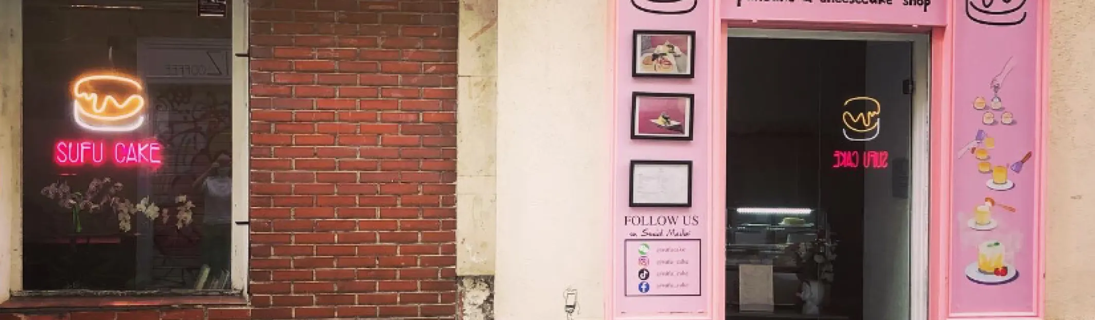Fachada rosa de Sufu Cake con taburetes de madera y neón encendido junto a la entrada del local.