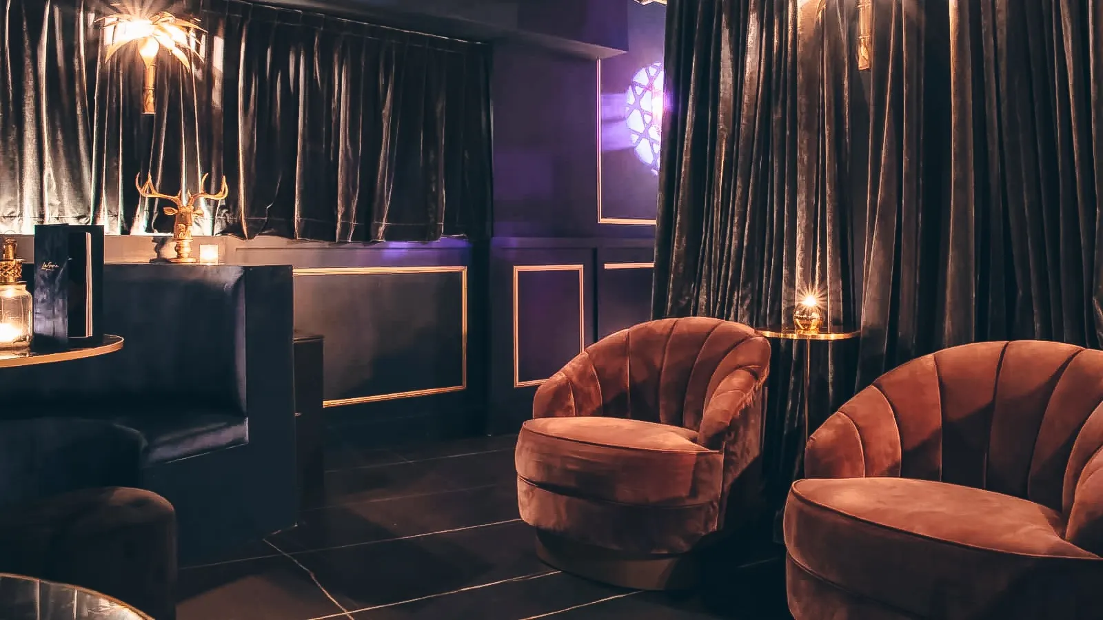 La Perla ofrece un ambiente íntimo con elegantes cortinas, sillones de terciopelo y detalles dorados que crean un espacio sofisticado.