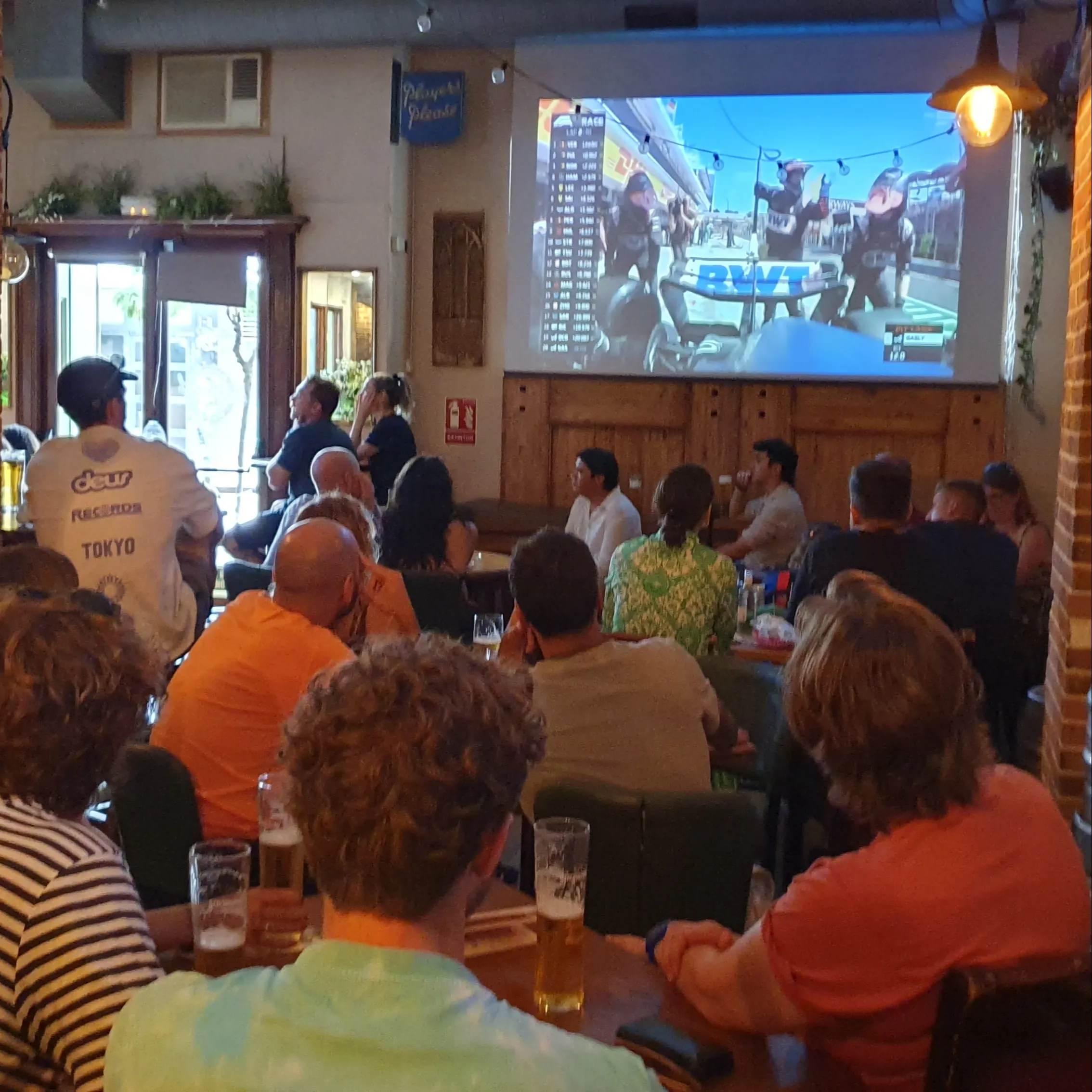 La imagen muestra un grupo de personas en el Flaherty´s, viendo un evento deportivo en una pantalla de televisión.