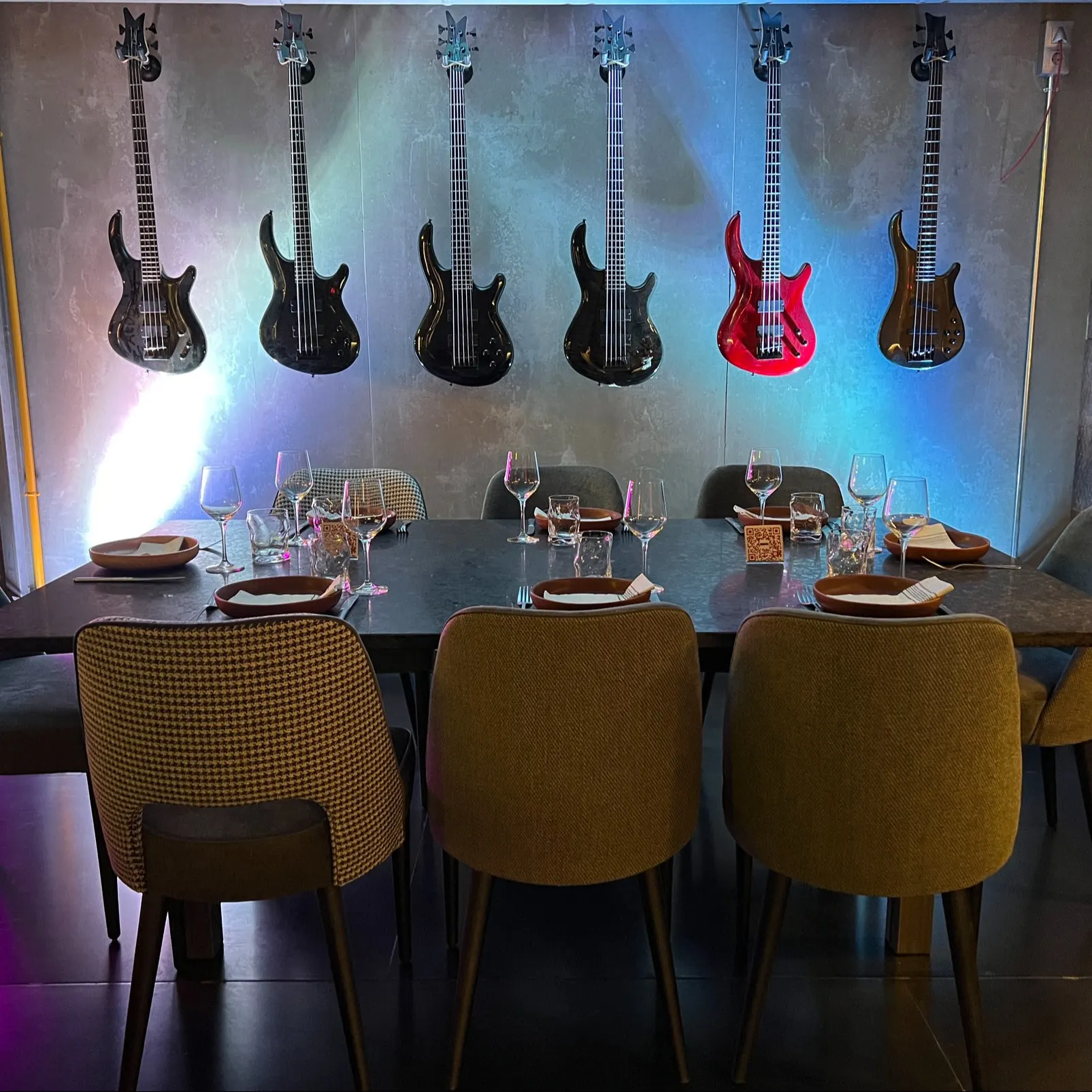 Un comedor en Bosco con una mesa elegantemente montada para ocho personas, rodeada de sillas modernas y decorado con guitarras colgantes en la pared.