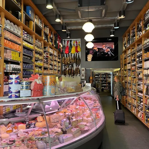 Interior del Colmado Quílez, un espacio tradicional y gourmet con estanterías llenas de productos selectos, una vitrina repleta de quesos y embutidos.